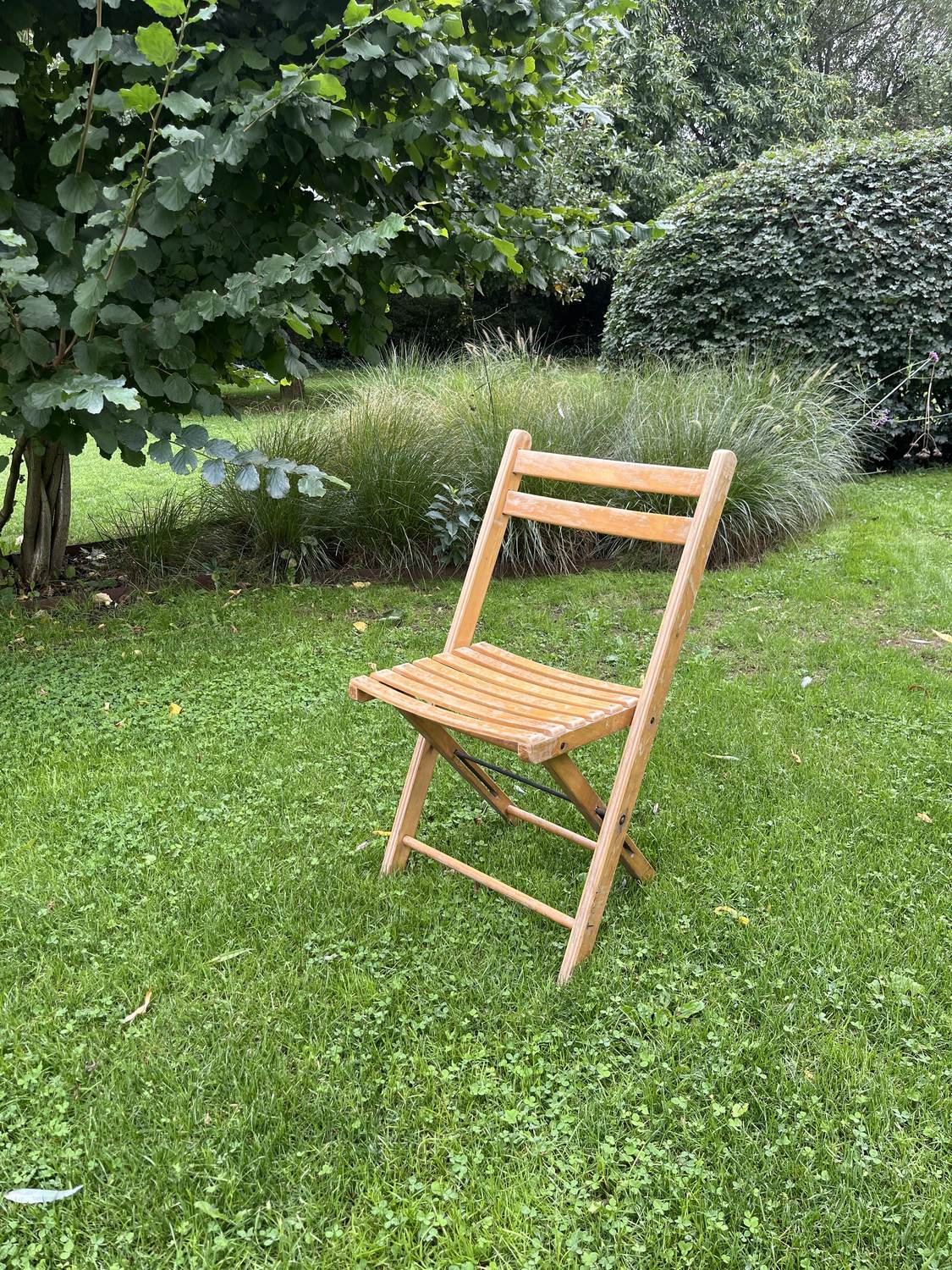 Houten klapstoel met gebogen zitting op het gras