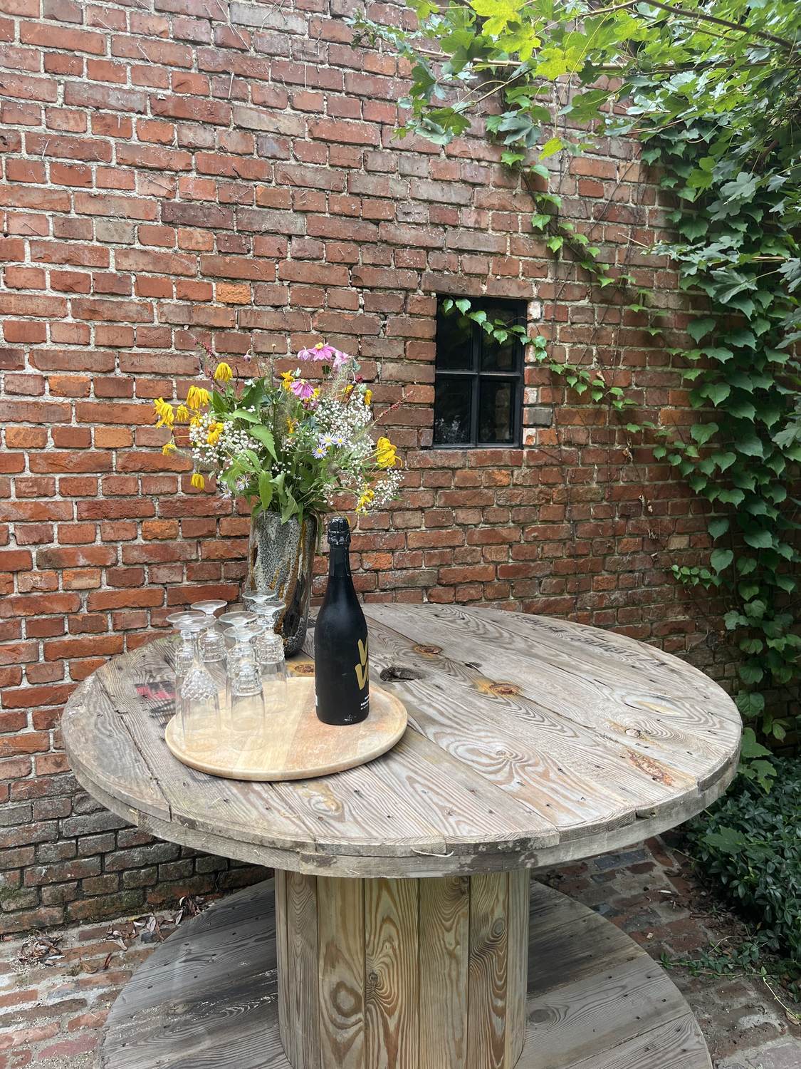 Ronde statafel gemaakt van een houten kabelhaspel met bloemen en glazen
